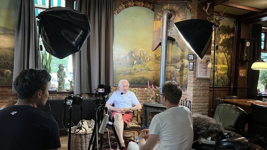 A two-camera interview set-up with an elderly cyclist in a village café